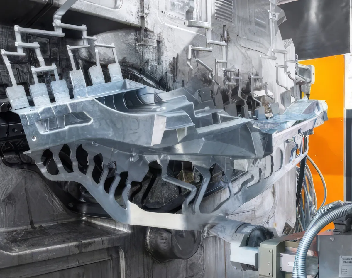 Freshly cast aluminum component being extracted from a die casting machine