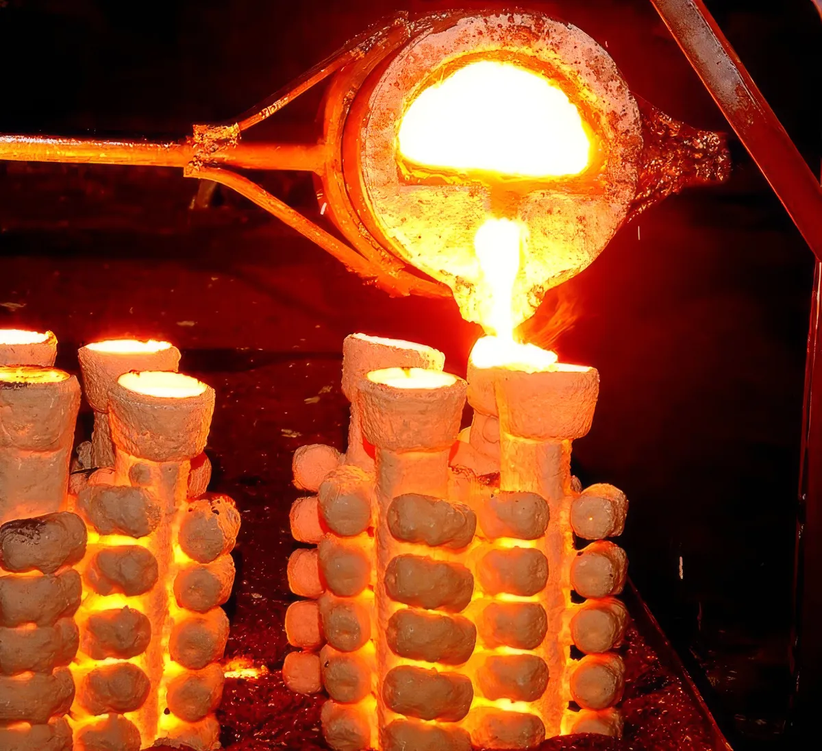 Molten metal being poured into glowing investment casting shells
